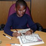 Amblyopia patching therapy: a child wearing an adhesive occlusive eye patch over the stronger eye while colouring, part of standard occlusion treatment for amblyopia